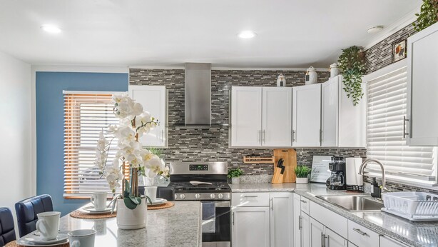 Una cocina moderna con armarios blancos, una estufa de acero inoxidable y un horno empotrado.