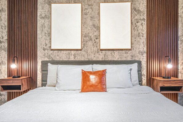 A bed with white bedding, a wooden headboard, and two bedside tables with lamps.