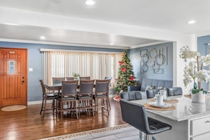 A dining area with a wooden table and chairs, a Christmas tree, and a seating area with a sofa and coffee table.