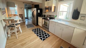 A kitchen with wooden flooring, a dining table with chairs, a refrigerator, a stove, and cabinets. - Fabulous Farm Stay (Crozier)