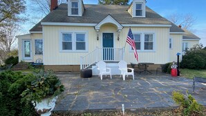 A two-story house with a front porch, a flag, and a stone patio. - Fabulous Farm Stay (Crozier)