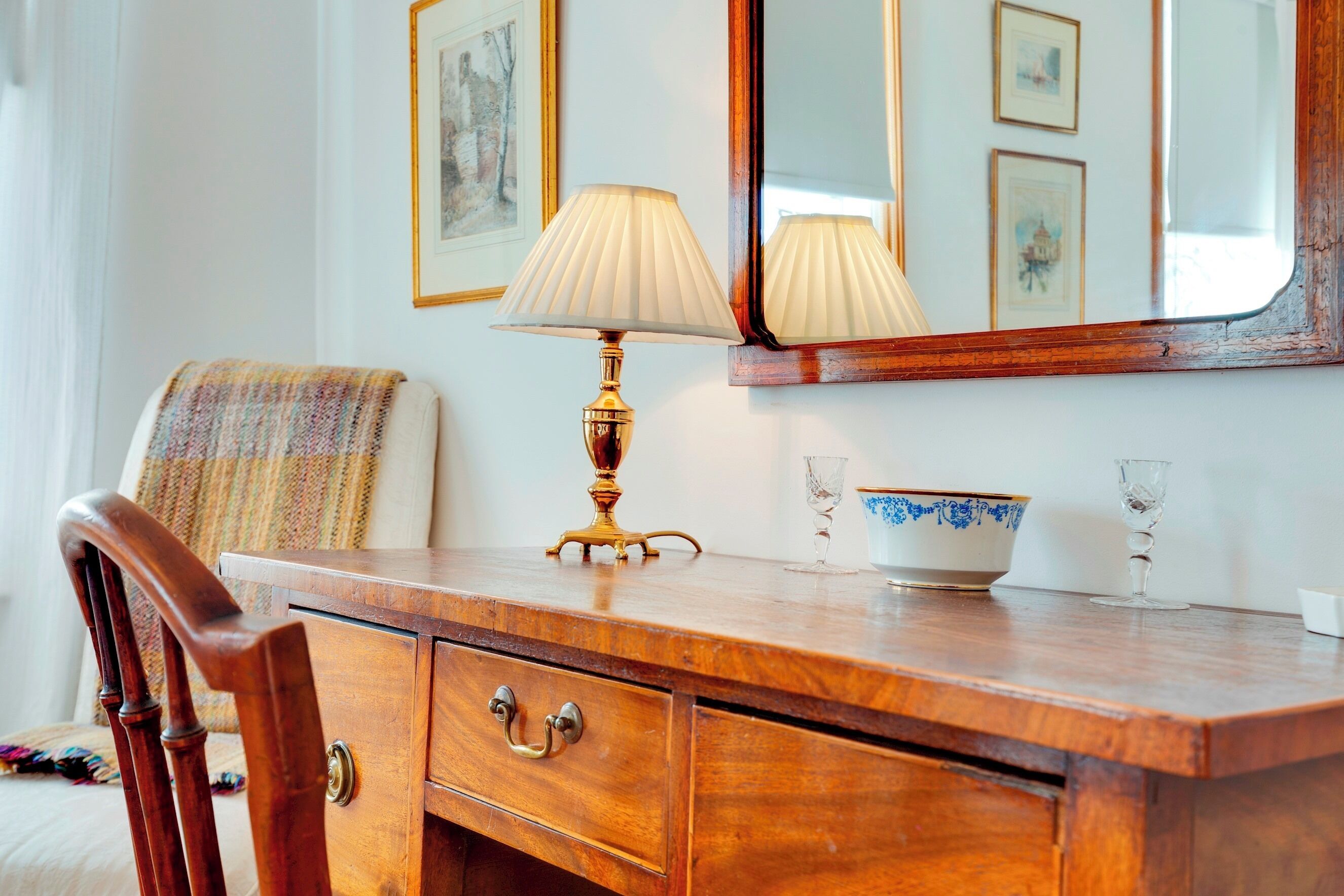 Een houten dressoir met een lamp, een schaal en een glas.