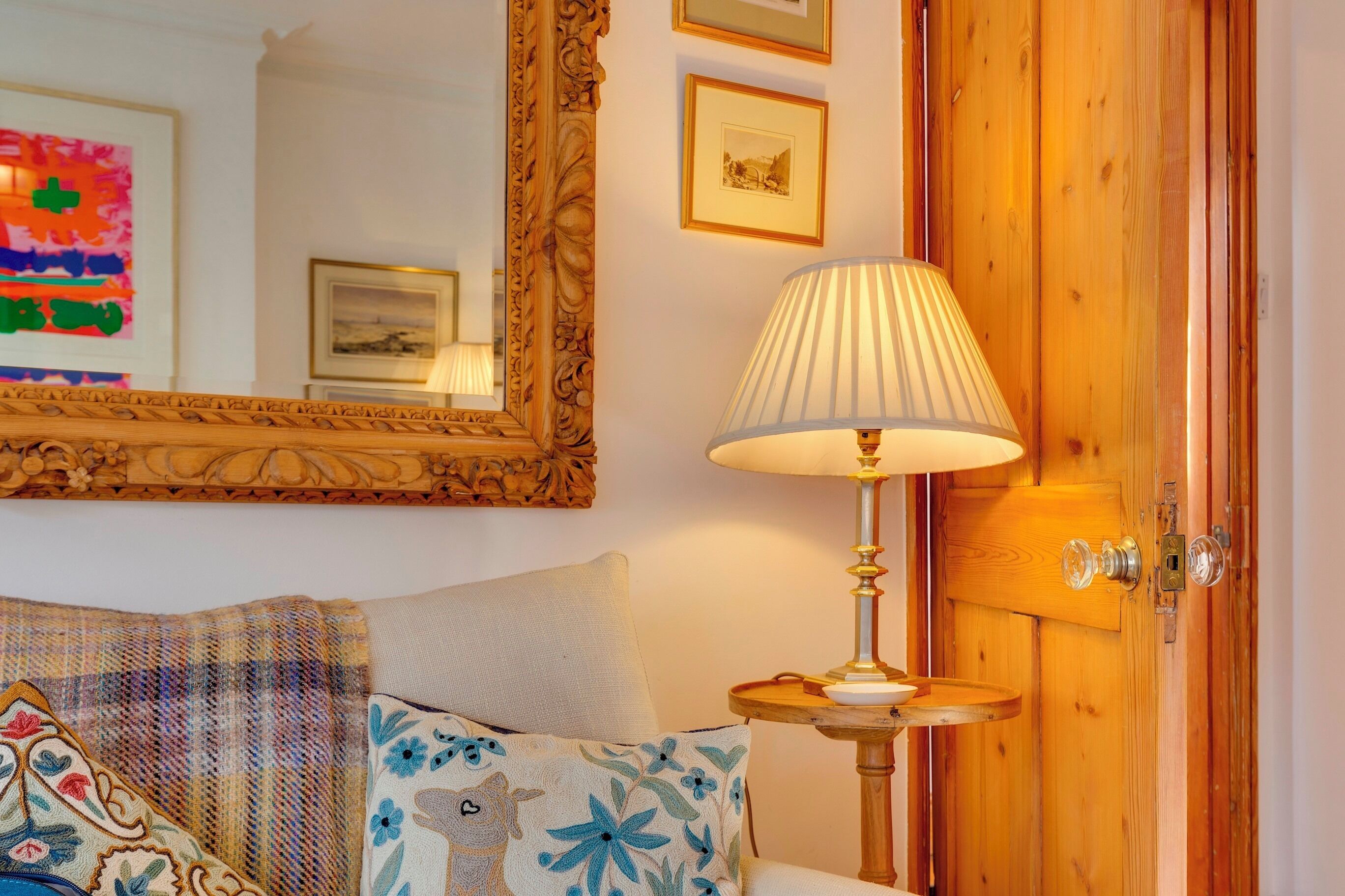 A cozy room with a bed, a lamp, a mirror, and wooden doors.
