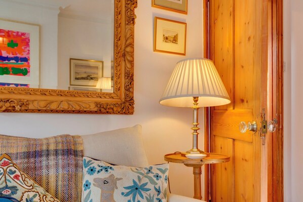 A cozy room with a bed, a lamp, a mirror, and wooden doors.