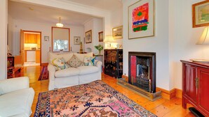 A living room with a fireplace, a sofa, a patterned rug, and a dining area with a table and chairs. - Pass the Keys | Charming Cottage in the City Centre | Free Parking (Cambridge)