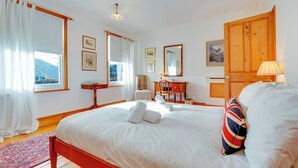 A hotel room with a large bed, a desk, a chair, and a wardrobe. - Pass the Keys | Charming Cottage in the City Centre | Free Parking (Cambridge)