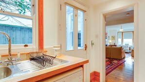 A kitchen with a sink, a dish rack, and a window with a view of a tree. - Pass the Keys | Charming Cottage in the City Centre | Free Parking (Cambridge)