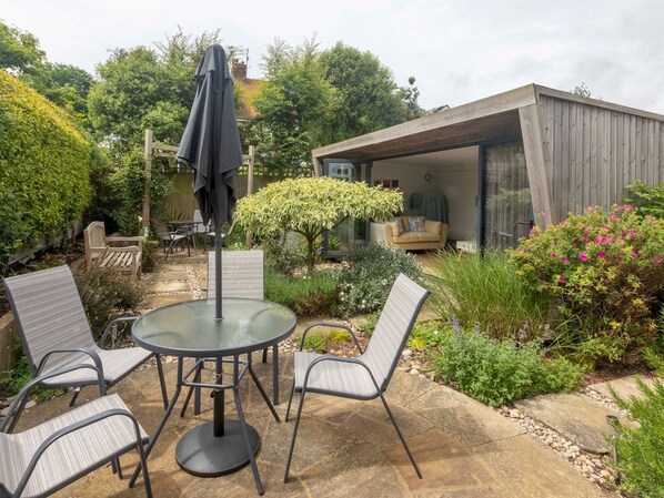 Relax in a serene outdoor space surrounded by lush greenery and a structure with glass doors.
