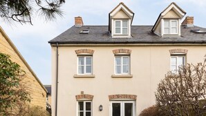 Ein zweistöckiges Haus mit Flachdach, Dachgauben und einer Haustür mit Glasfeldern.