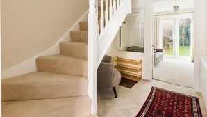Eine Treppe mit beigefarbenem Teppich, die zu einer Zwischenebene führt.