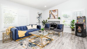 Uma sala de estar moderna com um sofá azul, duas poltronas, uma mesa de centro de vidro e uma lareira.