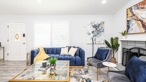Uma sala de estar moderna com um sofá azul, uma mesa de centro de vidro e uma lareira.