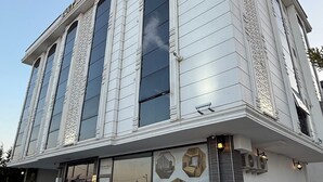 A building with a large entrance, a covered outdoor seating area, and a decorative wall with hexagonal mirrors.