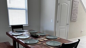A dining area with a wooden table set for four, a bench, and a chair. - Your Home by the Orlando Parks (Davenport)