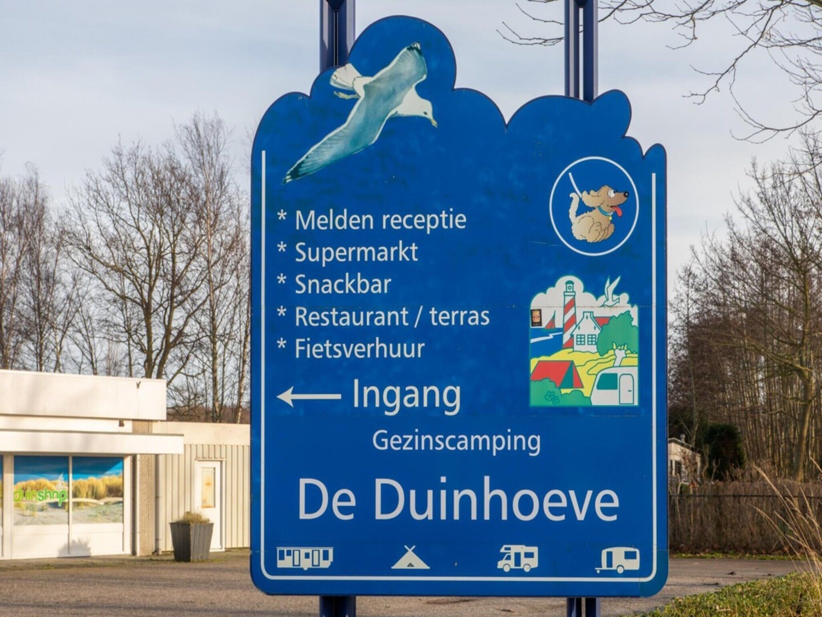 A directional sign for De Duinhoeve with amenities listed including a reception, supermarket, snack bar, restaurant, and toilet.
