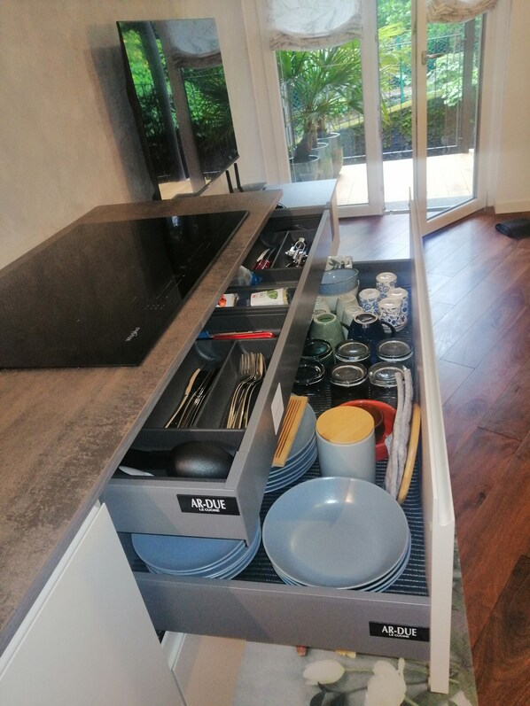 A kitchen area with a built-in drawer containing plates, bowls, and utensils. - Relaxing Break Lario (Gravedona)