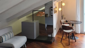 Une chambre de style loft moderne, avec un plafond en pente, un bureau intégré, un canapé et un coin repas avec des chaises.