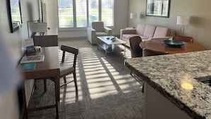 Ein modernes Wohnzimmer mit Sofa, Sesseln, einem Couchtisch und einer Küchenzeile mit Granitplatte.