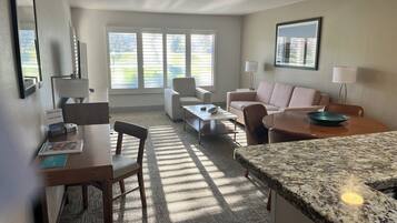 Een moderne woonkamer met een bank, stoelen, een salontafel en een keuken met een granieten aanrecht.