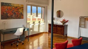 Un salon moderne avec une grande fenêtre, un bureau, une chaise, un canapé et un radiateur.