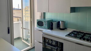 Une cuisine équipée d’une cuisinière à gaz, d’un four à micro-ondes, d’un grille-pain et d’une bouilloire.