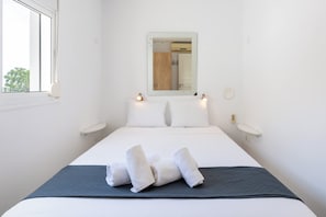 Une chambre d’hôtel avec un lit, une fenêtre, un miroir et une table de chevet.
