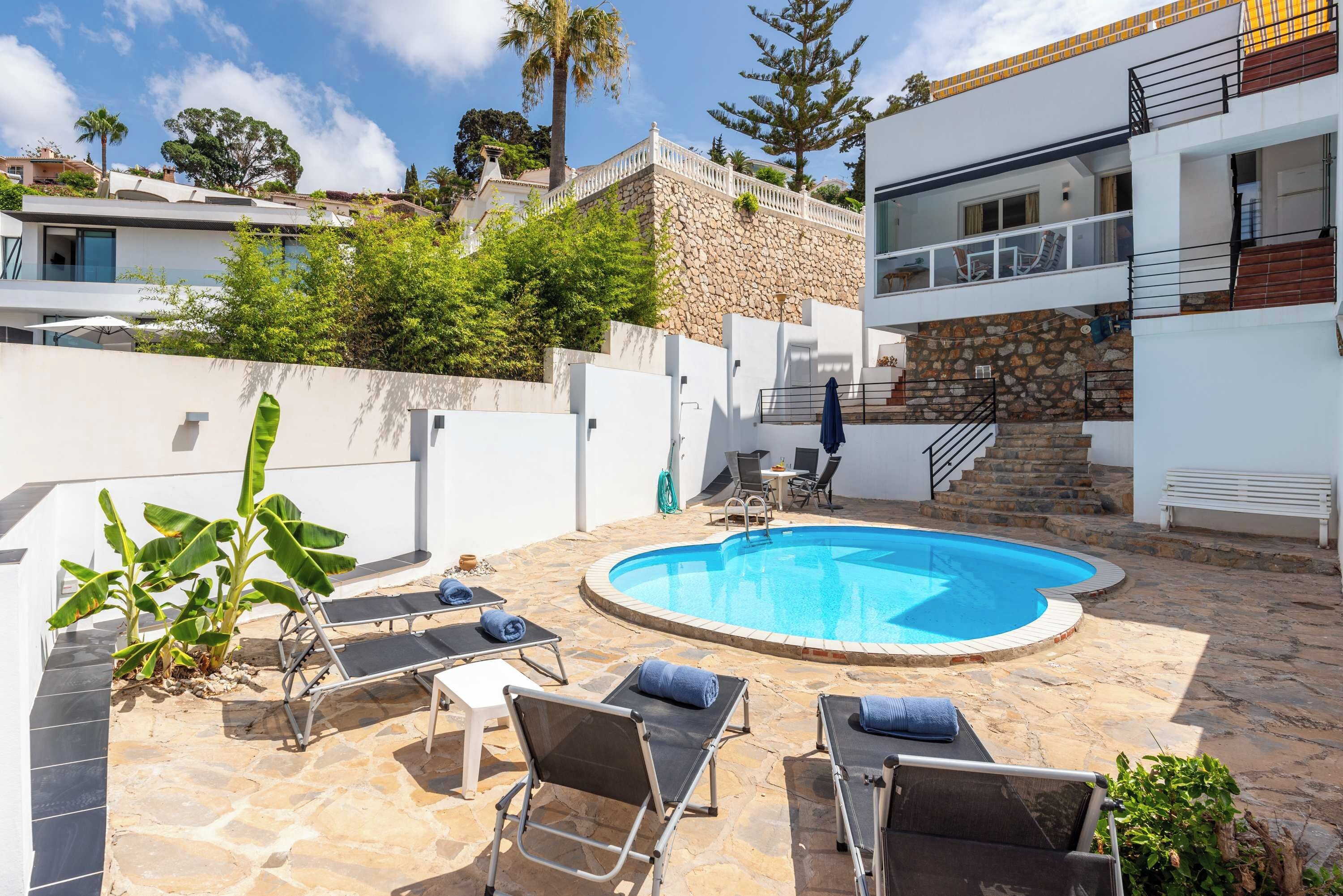 A swimming pool with lounge chairs and a stone wall.