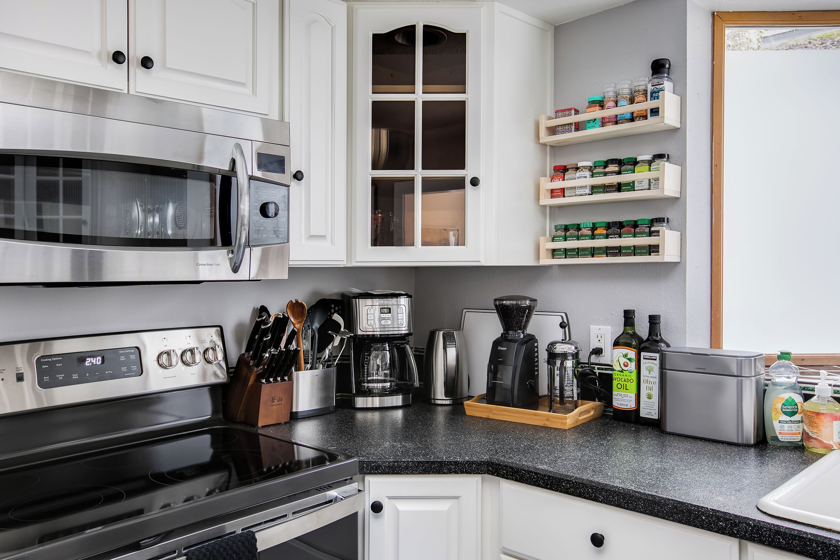 Una cocina moderna con electrodomésticos de acero inoxidable, armarios blancos y una zona para café.