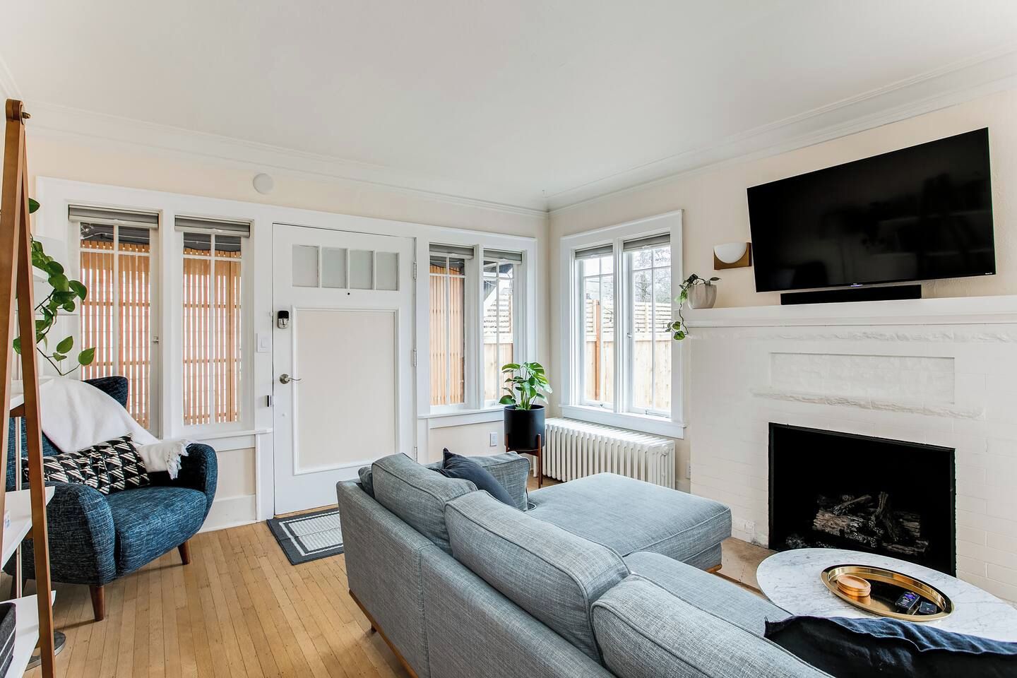 Ein Wohnzimmer mit einer Couch, einem Fernseher, einem Kamin und einem Fenster mit Jalousien.