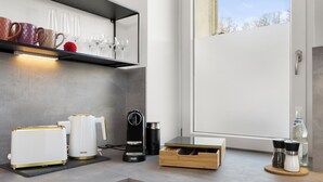 A modern kitchen with a coffee maker, toaster, and a wooden drawer unit.
