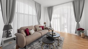 A modern living room with a sofa, a small table, a lamp, and a vase with flowers.