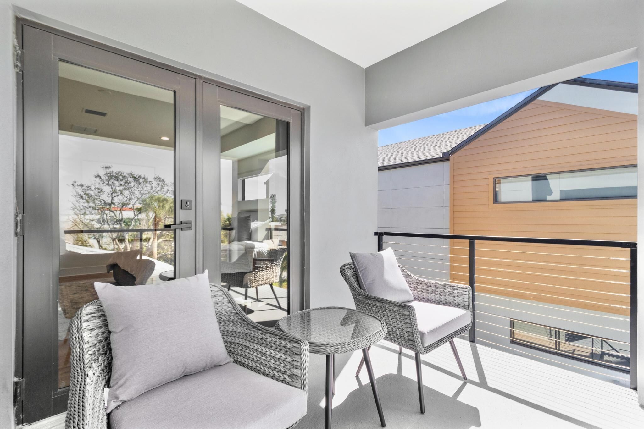 Ein Balkon mit Rattanmöbeln und einer Glastür zum Außenbereich.