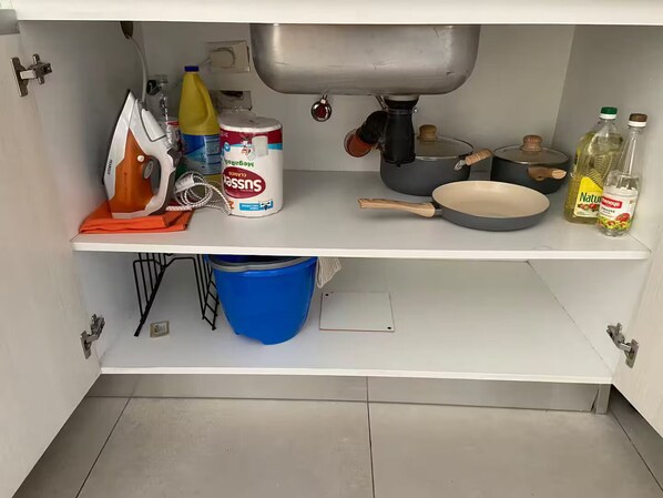 A kitchen with a sink, a stove, and various kitchen items on the counter.