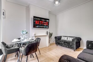 Relax in this stylish living room with a flat-screen TV, dining area, and comfortable seating.