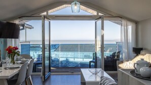 Une chambre moderne dotée d’une grande porte vitrée donnant sur un balcon avec vue sur la mer.