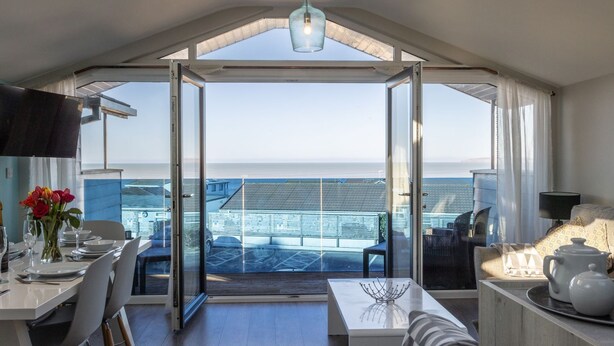 A modern room with a large glass door leading to a balcony with a view of the sea. - 3 Bed pet friendly Beach House with sea views (Westward Ho!)