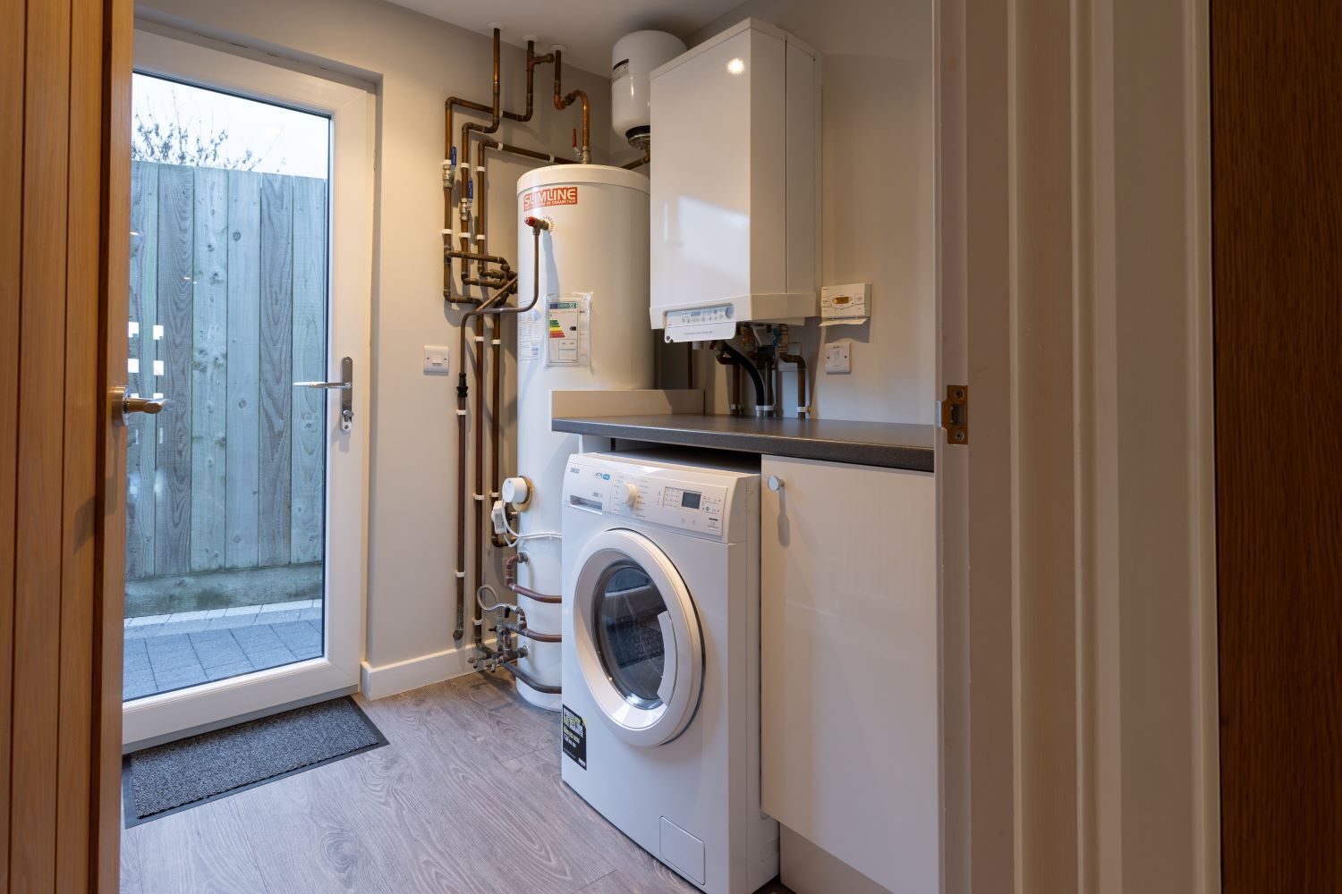 A compact laundry room with a washing machine, a water heater, and a small countertop.