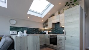 A modern kitchen with a skylight, wooden cabinets, and a green-tiled backsplash. - 3 Bed pet friendly Beach House with sea views (Westward Ho!)