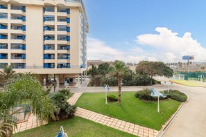 A hotel with multiple floors, a courtyard with palm trees, and a clear sky. - Patacona Iconic I . WiFi + PK + A/ Conditioning + Pool (Alboraya)