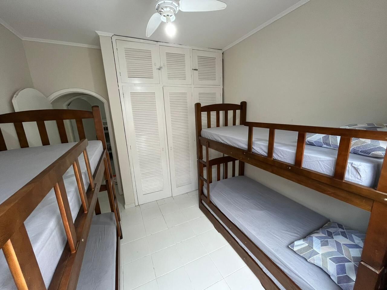 Una stanza del dormitorio con letti a castello, una ventola a soffitto e un insieme di porte impanellate bianche.