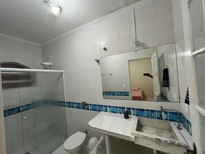Een badkamer met een douche, toilet, wastafel en een spiegel.