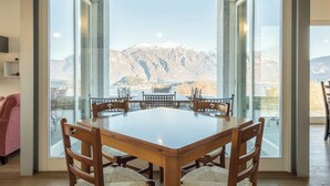A dining area with a large table and chairs, large windows offering a mountain view. - Villa Corvina by My Villa Collection (Tremezzo)