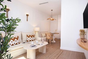 A modern living room with a sofa, coffee table, and dining area. - Genteel Home Gamazo I (Seville)