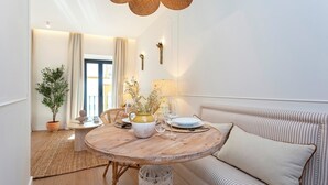 Een gezellige zithoek met een ronde houten tafel, een gestreept bankje en een potplant.