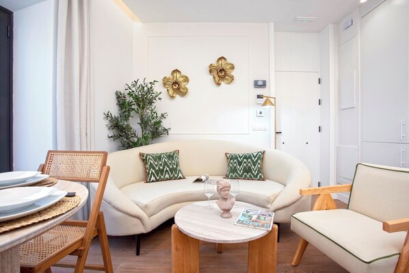 A modern living room with a sofa, chairs, a coffee table, and decorative wall art. - Apartment with pool in Seville. Gamazo Terrace II (Seville)