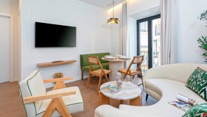 A modern living room with a flat-screen TV, wooden chairs, a round table, and a sofa. - Genteel Home Gamazo Terrace II (Seville)