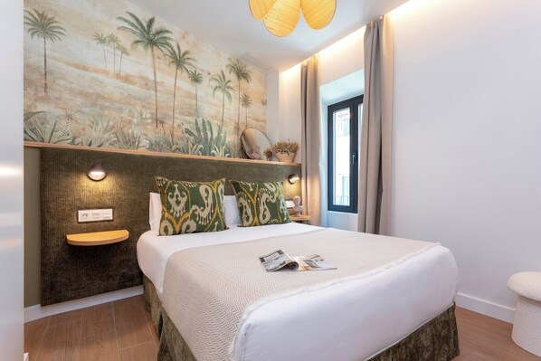 A bedroom with a bed, a nightstand, a mirror, and a wall mural. - Genteel Home Gamazo Terrace II (Seville)