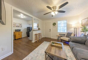 A spacious living room with a grey sofa, a wooden coffee table, and a ceiling fan.
