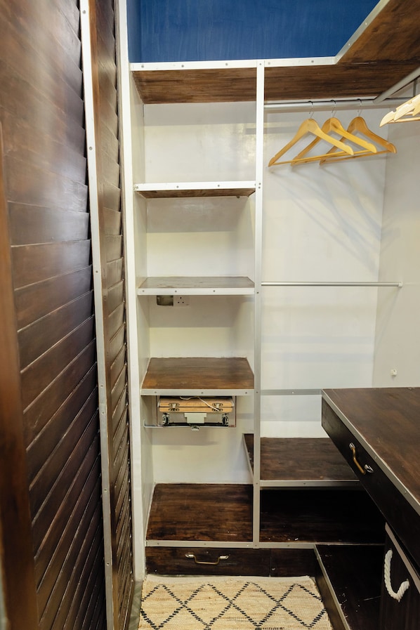 A walk-in closet with multiple shelves, a hanging rod, and a wooden dresser.