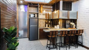 A modern kitchen with a built-in refrigerator, bar stools, and pendant lighting. - Chic 1BR Retreat: Steps to Rasfannu Beach & Malé’s Best (Malé)
